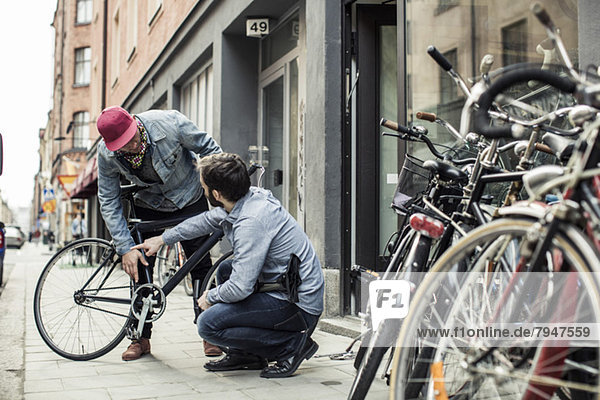 Young man explaining bicycle problems to repairman outside workshop