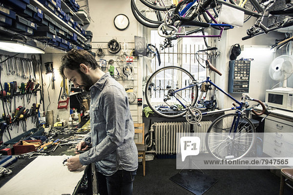 Profilaufnahme eines mittleren Erwachsenen  der in einer Fahrradwerkstatt arbeitet.