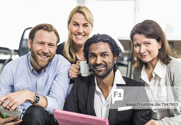Porträt glücklicher multiethnischer Geschäftsleute  die zusammen im Büro sitzen