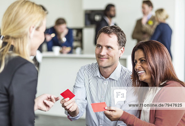 Business people giving business card to woman in office