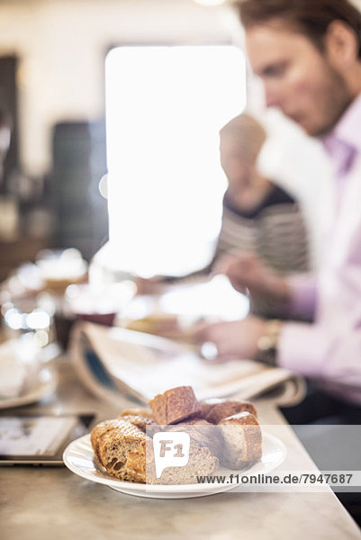 Brotstücke auf dem Restauranttisch mit Geschäftsleuten im Hintergrund
