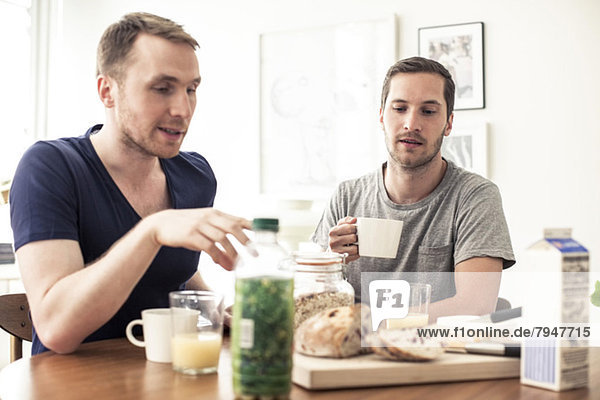 Homosexuelles Paar beim gemeinsamen Frühstück am Tisch zu Hause