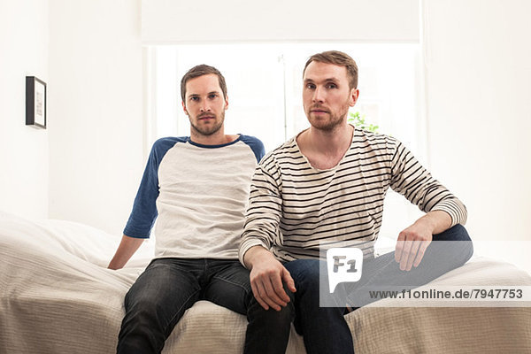 Portrait of homosexual couple sitting on bed at home