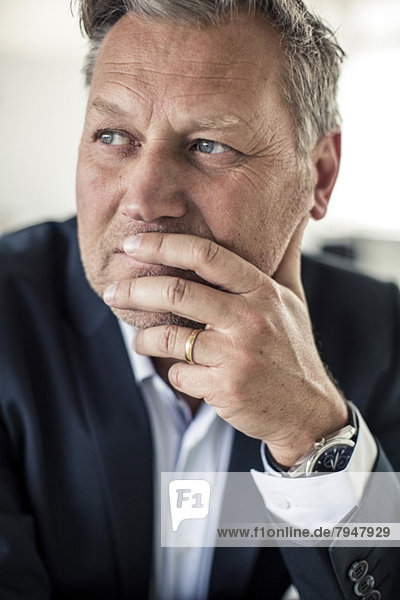 Thoughtful mature businessman looking away with hand on chin