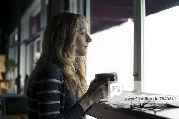 A young woman drinks coffee in a local cafe.