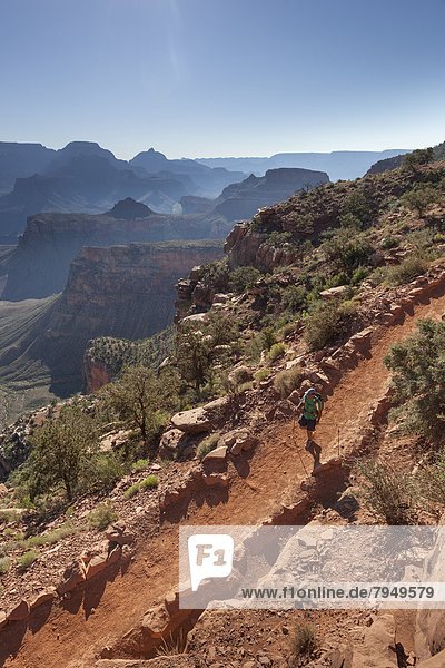 A man hiking on a trail with canyons in the background.