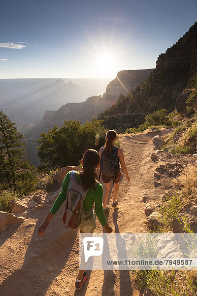 Two young women hikers hiking down a trail.
