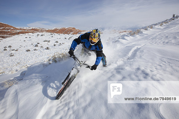 A mountain biker riding through a snowy desert landscape.