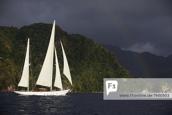 A classic yacht sails along the coast of St. Lucia with the Pitons in the background.