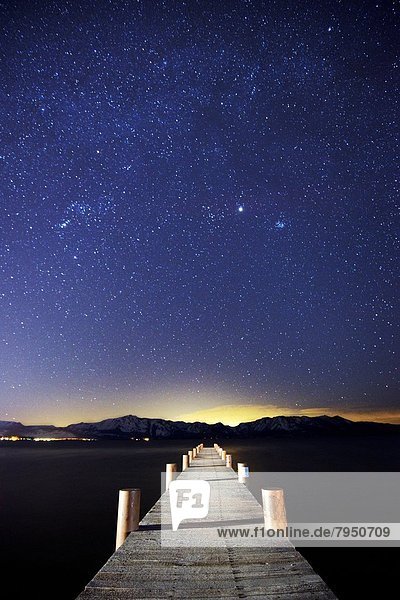 A pier on the east shore of Lake Tahoe is illuminated at night with stars in the sky in Lake Tahoe  NV.