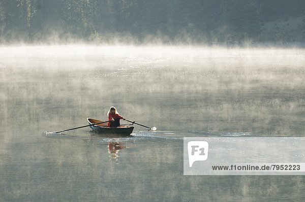 A woman rowing a scull boat a foggy morning near Creede  Colorado.