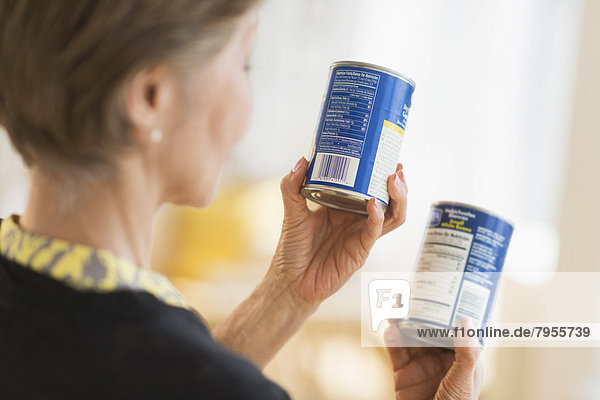 Senior woman reading labels on canned food