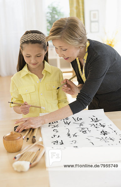 Grandmother and granddaughter (8-9) painting japanese symbols