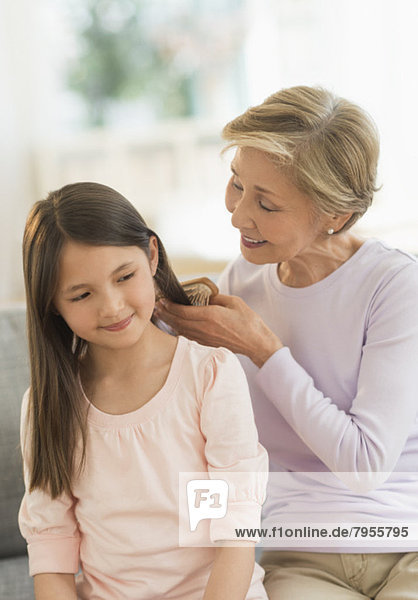 Grandmother brushing granddaughter's (8-9) hair