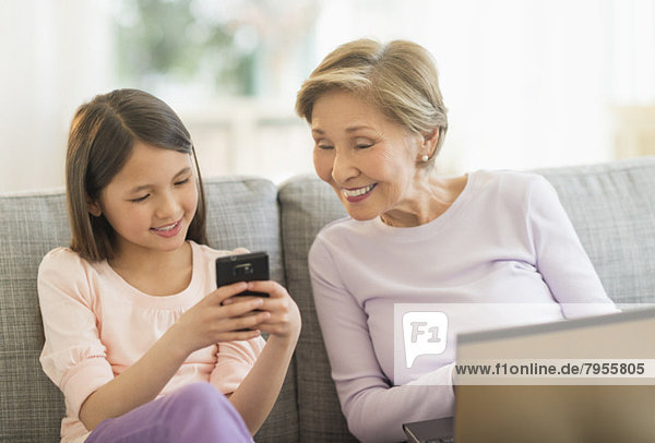 Handy  sitzend  benutzen  Notebook  Couch  Enkeltochter  Großmutter  5-9 Jahre  5 bis 9 Jahre