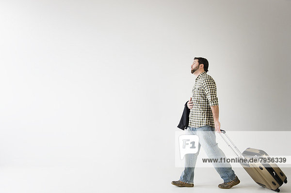 Side view of man walking with suitcase