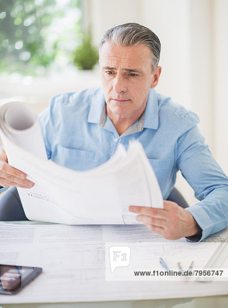 Portrait of man looking at blueprints in office