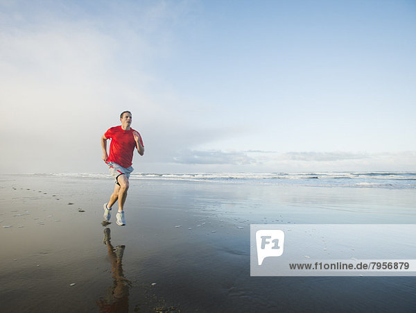 Young adult man running on beach