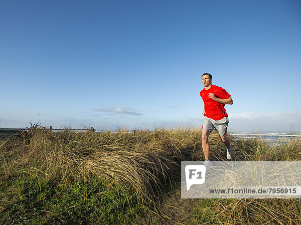 Young adult man running on dune