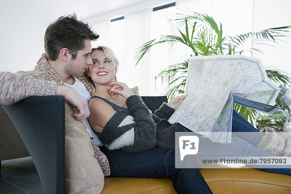 Couple sitting on sofa and reading map