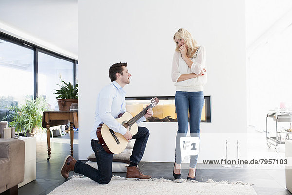Man playing guitar in front of woman