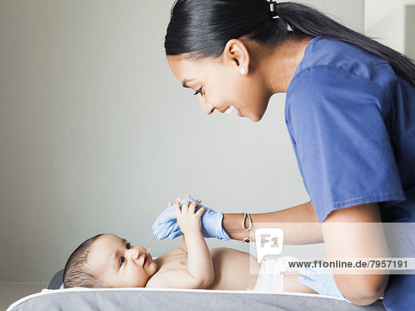 Nurse playing with ill baby boy (2-5 months)
