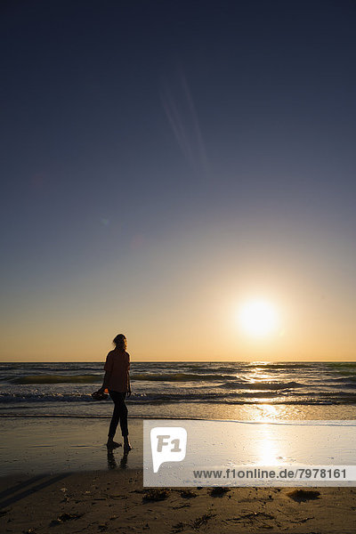 USA  Florida  Indian Rocks Beach  Mature woman walking on beach during sunset