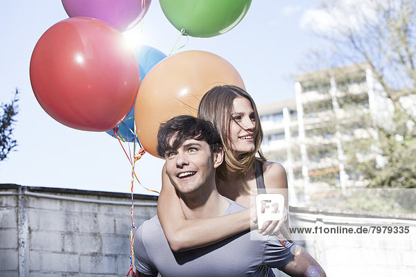 Young man giving piggyback ride to woman  smiling