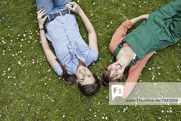 Junge Frauen auf Gras liegend  lächelnd