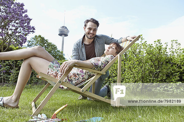 Deutschland  Köln  Junges Paar entspannt im Garten  lächelnd