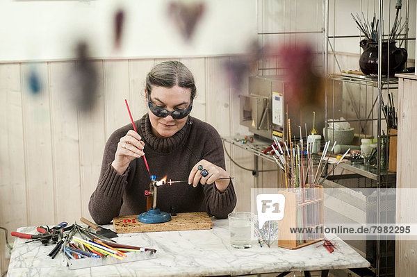Mature woman making glass beads