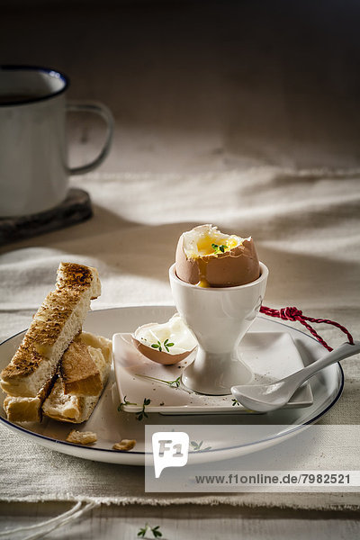 Ei mit geröstetem Weißbrot auf Teller und Kaffeetasse  Nahaufnahme