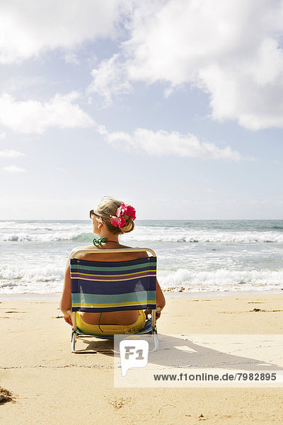 USA  Hawaii  Mittlere erwachsene Frau auf Liegestuhl am Strand sitzend
