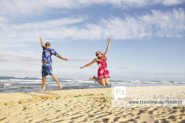 USA  Hawaii  Mid adult couple jumping on beach