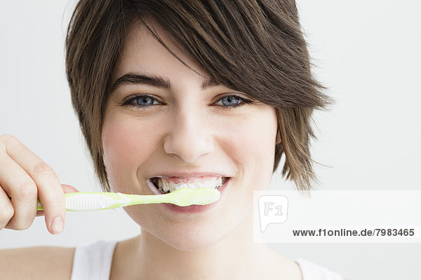 Portrait of young woman brushing teeth  close up
