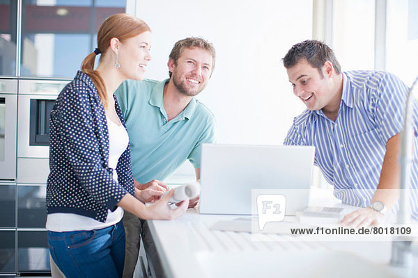 Young couple with salesman in kitchen showroom