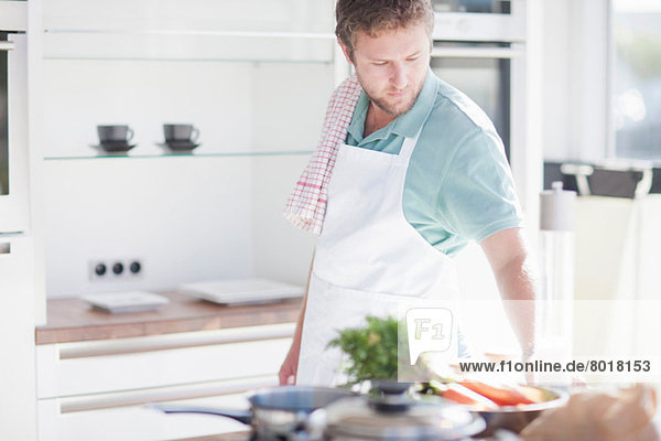 Junger Mann bei der Zubereitung des Essens in der Küche