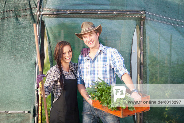 Junge Frau und Mann mit Gemüse aus eigenem Anbau