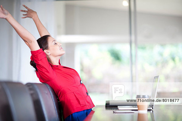 Young woman in office stretching