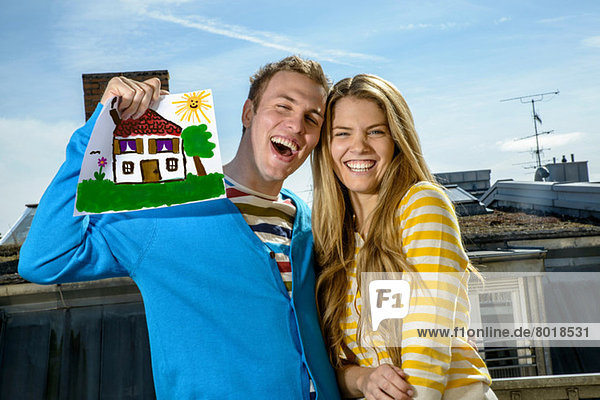 Junges Paar mit Hauszeichnung auf dem Dach