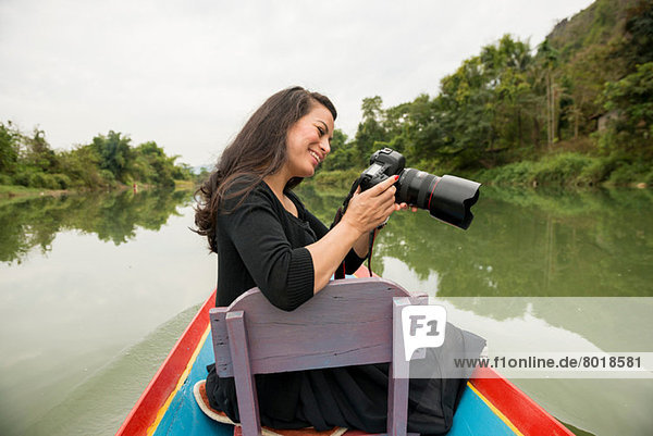 Woman with camera on boat on Nam Song River  Vang Vieng  Laos