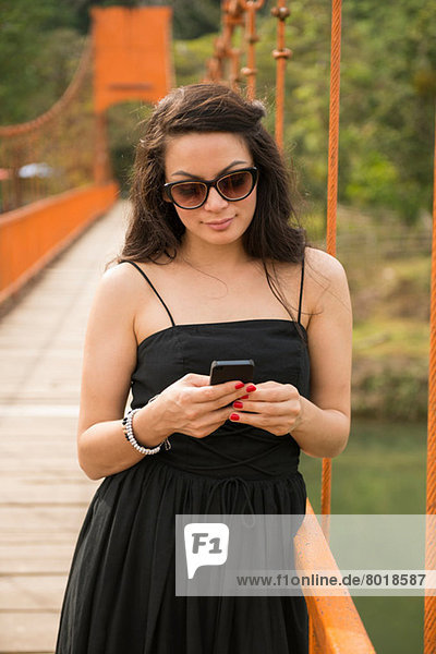 Frau mit Smartphone auf der Brücke
