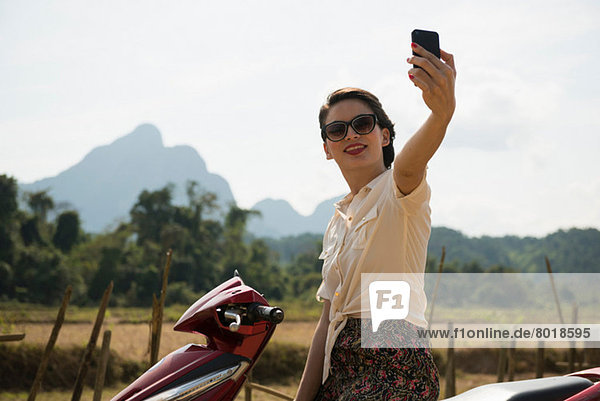 Frau fotografiert sich selbst auf Moped  Vang Vieng  Laos