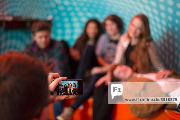Teenager-Junge fotografiert Gruppe von Freunden mit dem Smartphone