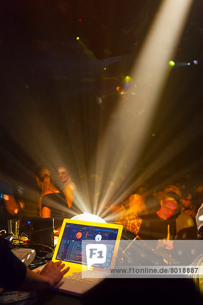 Nachtclubszene mit tanzenden Menschen  Discjockey-Mischpult mit Computer