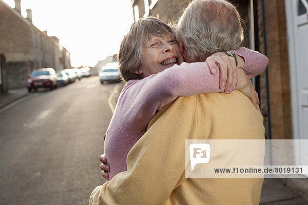 Ehemann und Ehefrau umarmen sich liebevoll auf der Straße