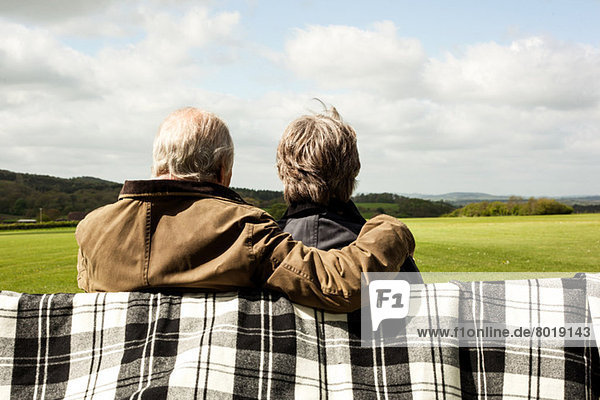 Rückansicht des Seniorenpaares  das die Landschaft auf dem Feld genießt.
