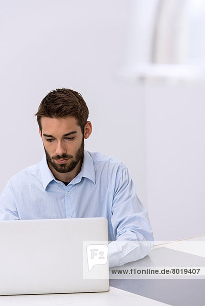 Junger Mann sitzt hinter dem Laptop im Büro
