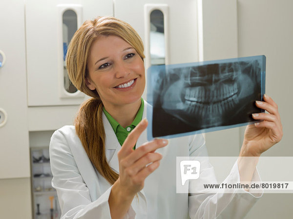 Dentist looking at x-ray  smiling