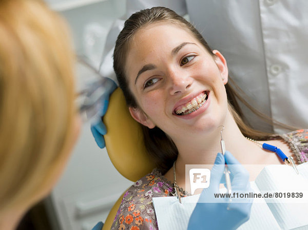Junge Frau lächelt im Zahnarztstuhl
